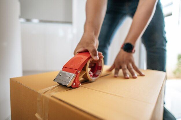 Close up hand of man use glue tape to close cardboard box sealing big box for packing moving new house concept selective focusx9cardboard box
