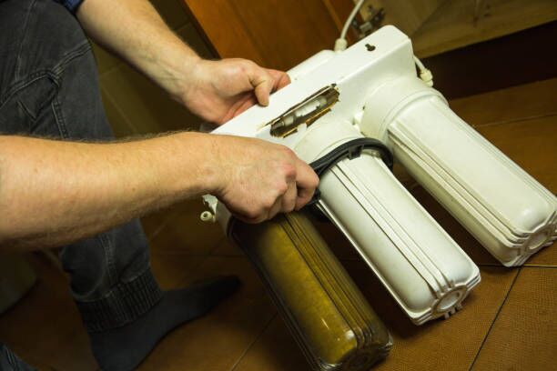 The master replaces dirty filters in the home water purification system. Human hands, filter, membrane. gun safe movers stock pictures, royalty-free photos & images