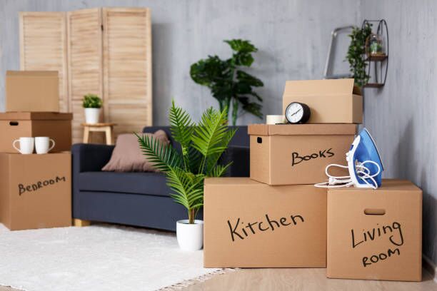 moving to new house - cardboard boxes with belongings stacked in living room after moving day moving to new house - brown cardboard boxes with belongings stacked in living room after moving day Apartment packing stock pictures, royalty-free photos & images