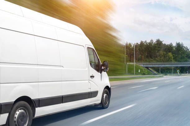 White modern delivery small shipment cargo courier van moving fast on motorway road to city urban suburb. Busines distribution and logistics express service. Mini bus driving on highway on sunny day White modern delivery small shipment cargo courier van moving fast on motorway road to city urban suburb. Busines distribution and logistics express service. Mini bus driving on highway on sunny day. moving company stock pictures, royalty-free photos & images