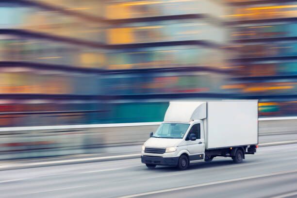 Fast delivery truck travelling through the city streets A delivery truck travelling fast on a city street with motion blurred office buildings in the background. moving company stock pictures, royalty-free photos & images