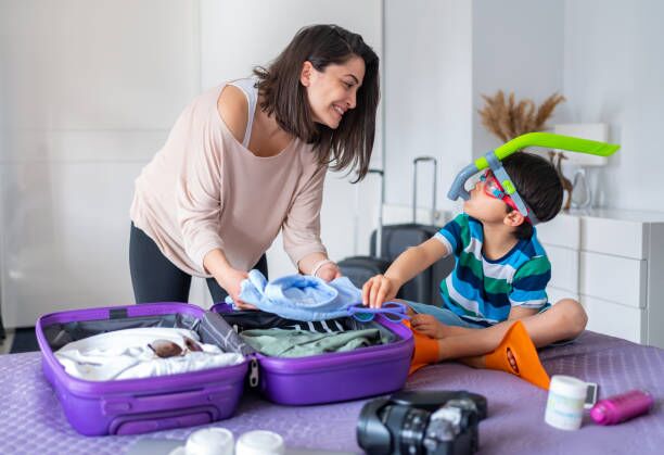 Packing For Holiday Mother And Son Preparing Travel Suitcase On Bed At Home children packing stock pictures, royalty-free photos & images