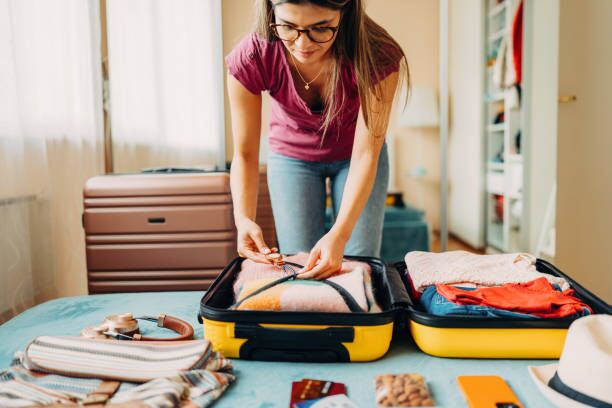 Woman packing suitcase for travel Woman packing suitcase for summer travel and using smart tag summer moving homes stock pictures, royalty-free photos & images