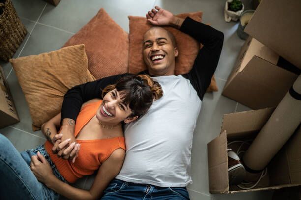 Happy young couple lying on the floor at new home Happy young couple lying on the floor at new home movers stock pictures, royalty-free photos & images