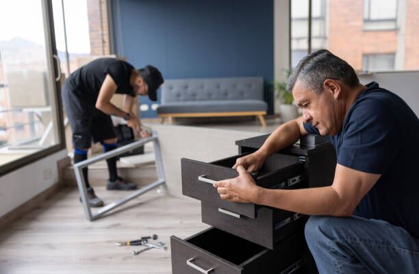 Professional movers disassembling pieces of furniture at an apartment Professional movers disassembling pieces of furniture at an apartment while packing in boxes - moving house concepts furniture disassembly stock pictures, royalty-free photos & images