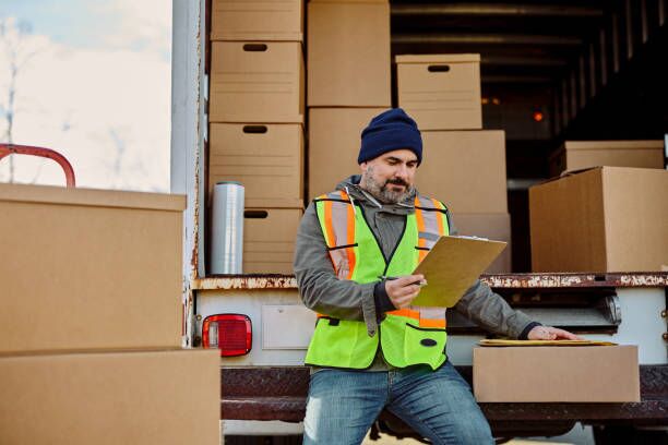 Truck driver going through shipment list in a van loaded with boxes. Mid adult courier analyzing delivery schedule list in delivery van. moving truck stock pictures, royalty-free photos & images