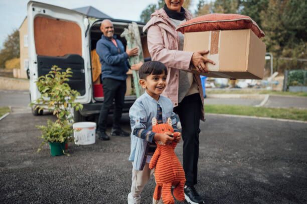 Arriving at New Home A shot of a mature couple wearing casual clothing unloading boxes and furniture from the rear of a moving van, ready to move in to their new bungalow together. They are with their young grandson. moving truck stock pictures, royalty-free photos & images