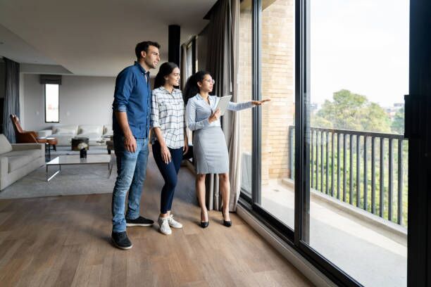 Real estate agent showing a house for sale to a couple Real estate agent showing a house for sale to a couple and looking at the view -home ownership concepts apartment stock pictures, royalty-free photos & images
