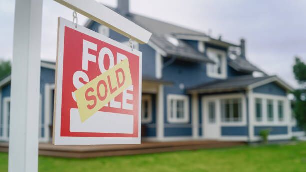 Close Up of a House Sold Sign on a Lawn in Front of a Big Modern House with Traditional Architecture. Housing Market Concept with Residential Property in the Countryside. Close Up of a House Sold Sign on a Lawn in Front of a Big Modern House with Traditional Architecture. Housing Market Concept with Residential Property in the Countryside. movers stock pictures, royalty-free photos & images
