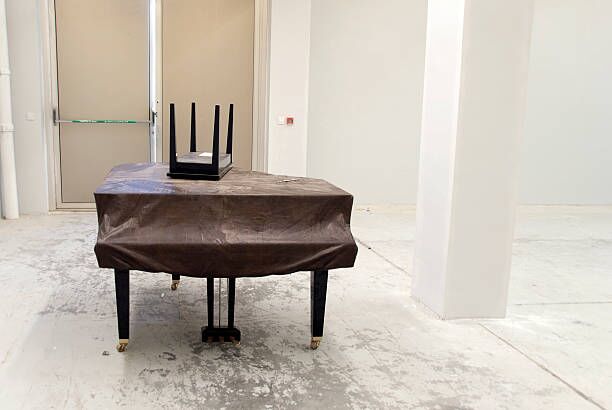 No More Music Covered piano in an empty room. piano movers stock pictures, royalty-free photos & images