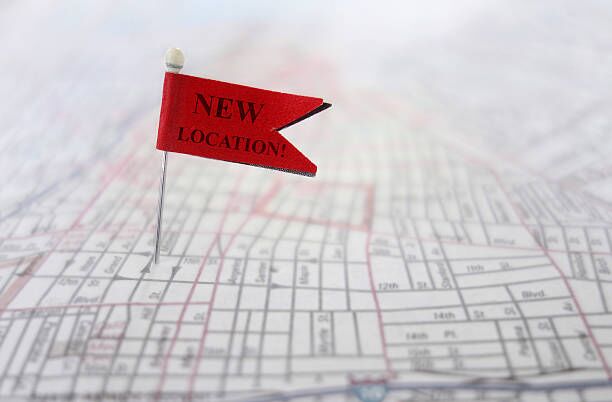 New Location Closeup of a New Location pin flag on a map office relocation stock pictures, royalty-free photos & images