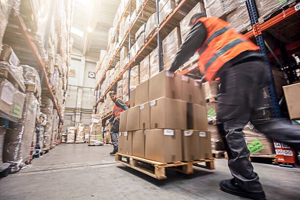 Motion blur of two men moving boxes in a warehouse Motion blur of two men moving boxes in a warehouse. moving company stock pictures, royalty-free photos & images
