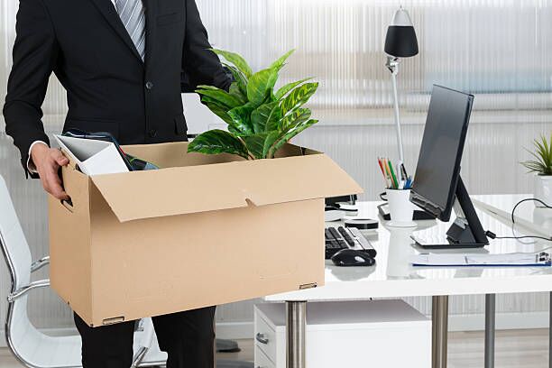 Midsection Of Businessman Carrying Cardboard Box Midsection of businessman carrying cardboard box by desk in office moving labor stock pictures, royalty-free photos & images