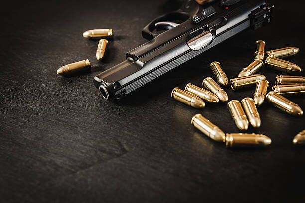 gun and bullets on the table black pistol and cartridges on a black wooden table gun moving stock pictures, royalty-free photos & images
