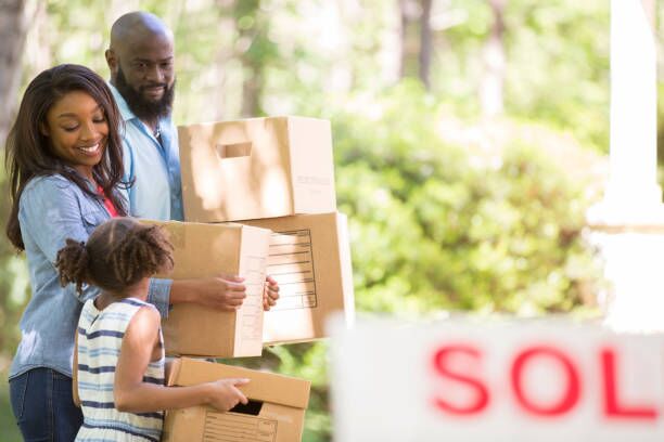 Family moving into new home. African descent family moving into a new home. Mother, father and daughter. Real estate sign. Home in background. Spring or summer season. summer moving homes stock pictures, royalty-free photos & images